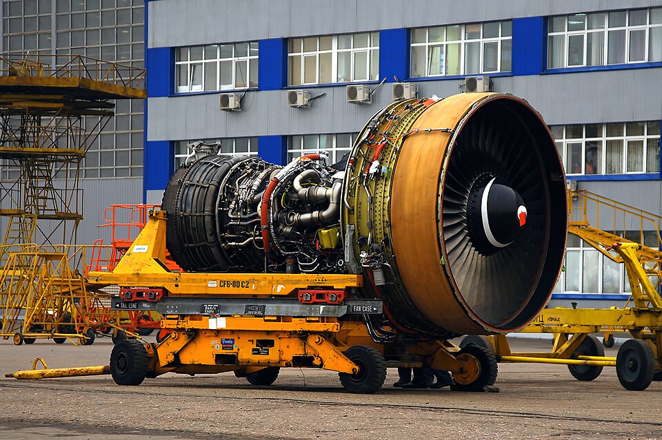 Тот самый CF6 в испытательном боксе General Electric — с человеком в белом халате внизу для масштаба. Именно это семейство стояло тогда на 747, DC-10 и A300, и именно с него началась программа снижения расхода. Фото из Национального архива США (NARA), общественное достояние.